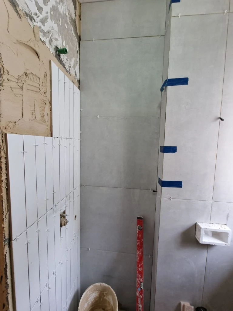 עבודות חיפוי קיר בשלב הביניים של שיפוץ מקלחת האורחים