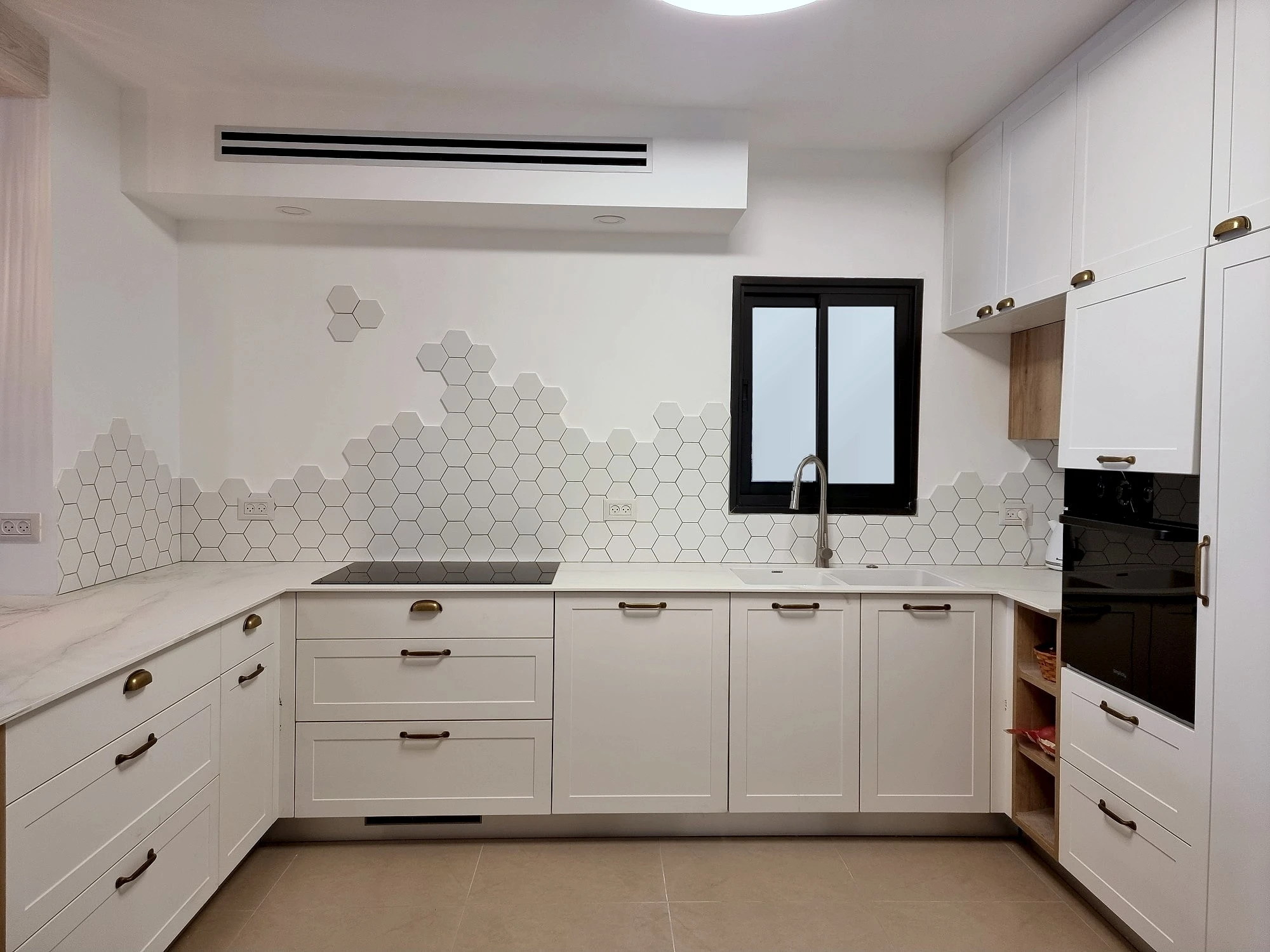 מבט ישר אל המטבח המוגמר עם ארונות חזית מסגרת ומשטח שיש קיסר