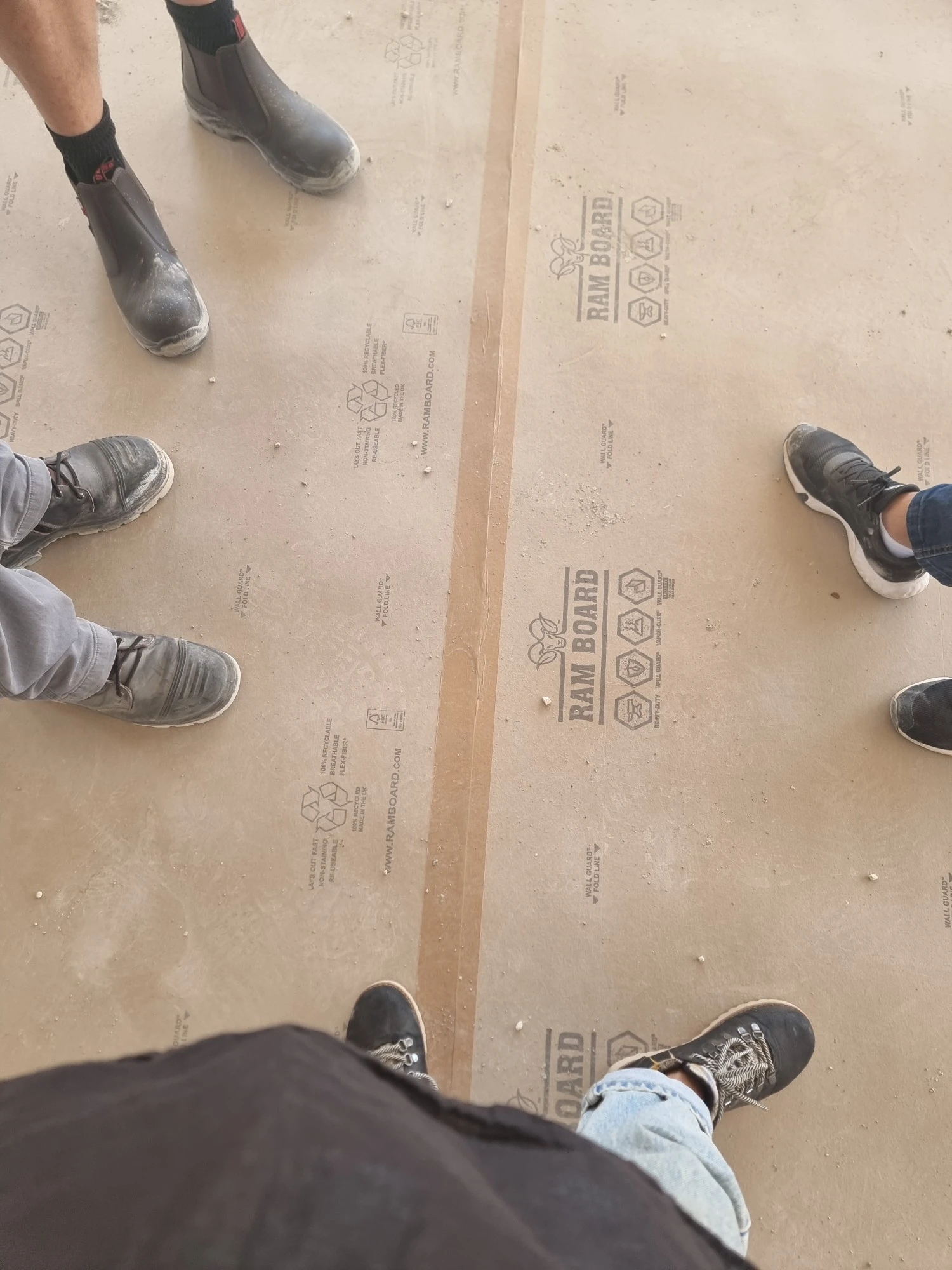 רצפת הבית מכוסה בלוחות הגנה, וצוות העבודה עומד סביב
