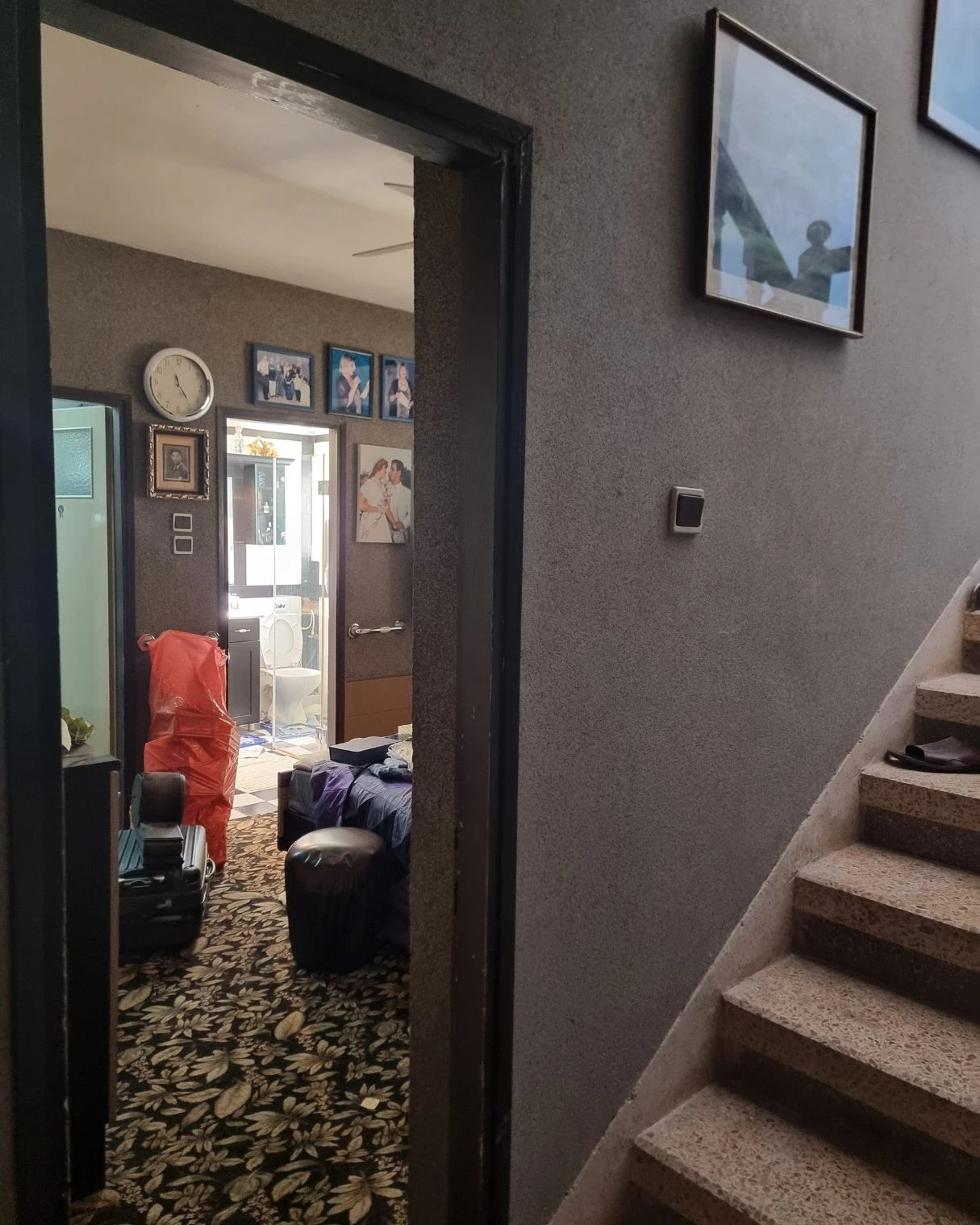 מבואה ישנה עם תמונות משפחתיות ומדרגות לפני השיפוץ