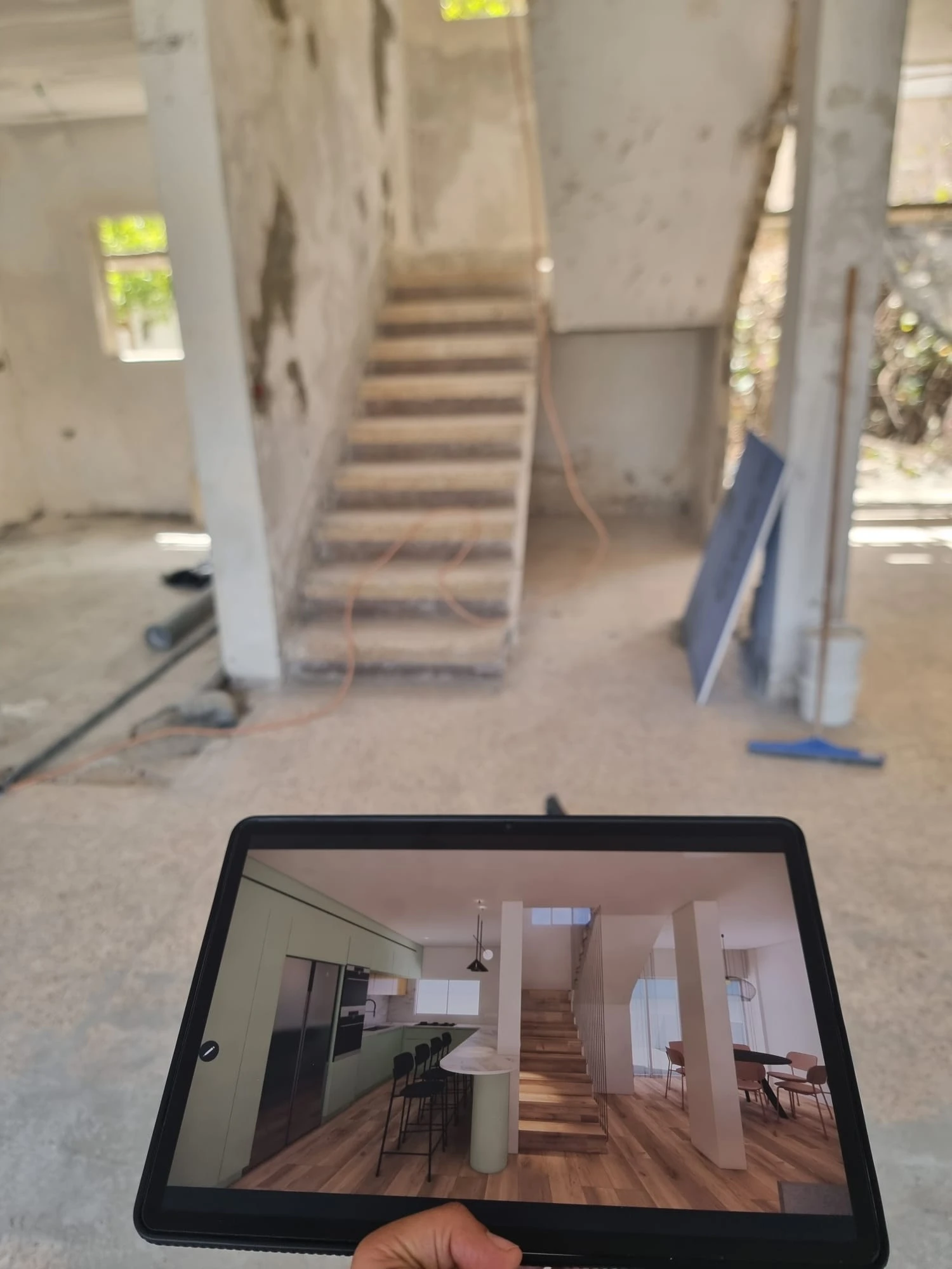 טאבלט מציג הדמיית עיצוב מול חלל הבית בשלד לאחר הריסה