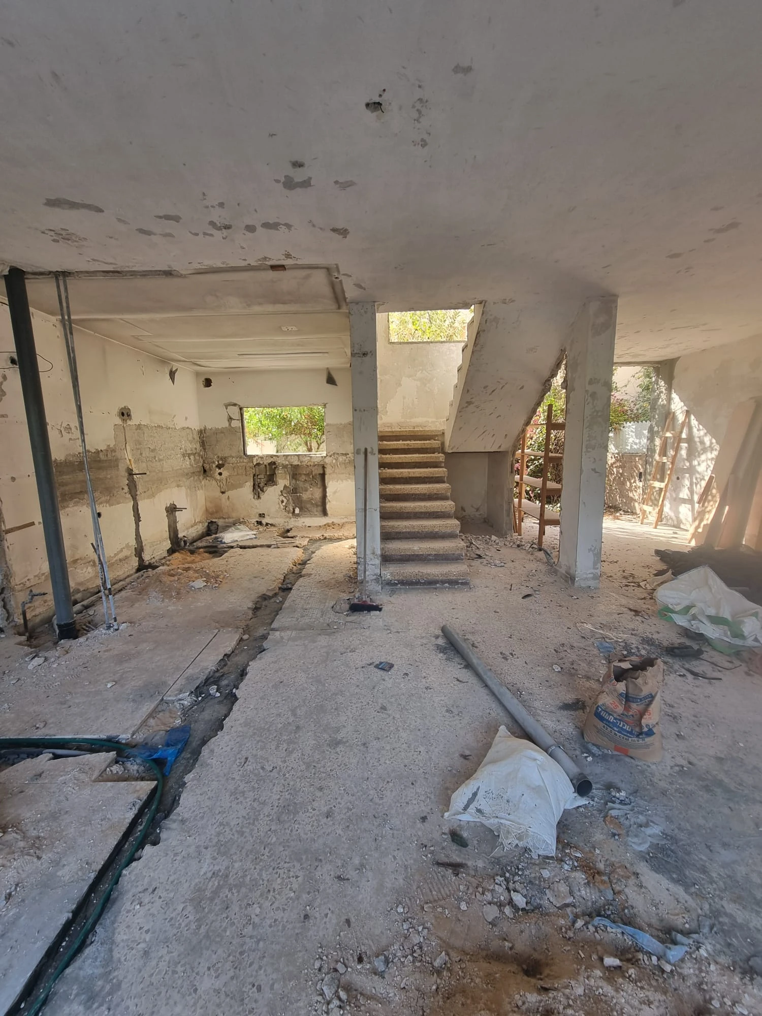 חדר בשלד בטון עם צנרת חשופה ומדרגות בזמן פירוק הבית
