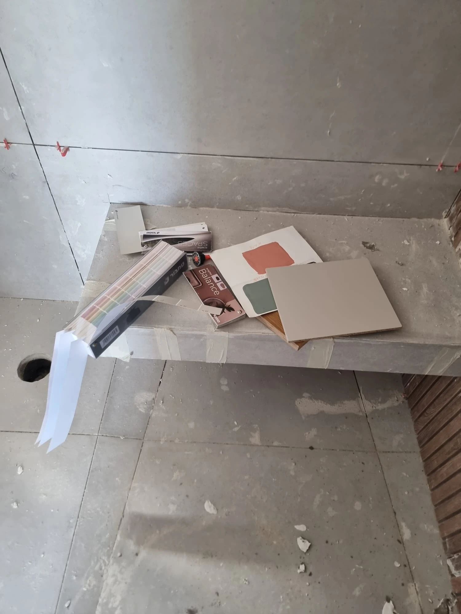 דוגמאות צבע וחיפוי מונחות על אדן בטון באתר השיפוץ