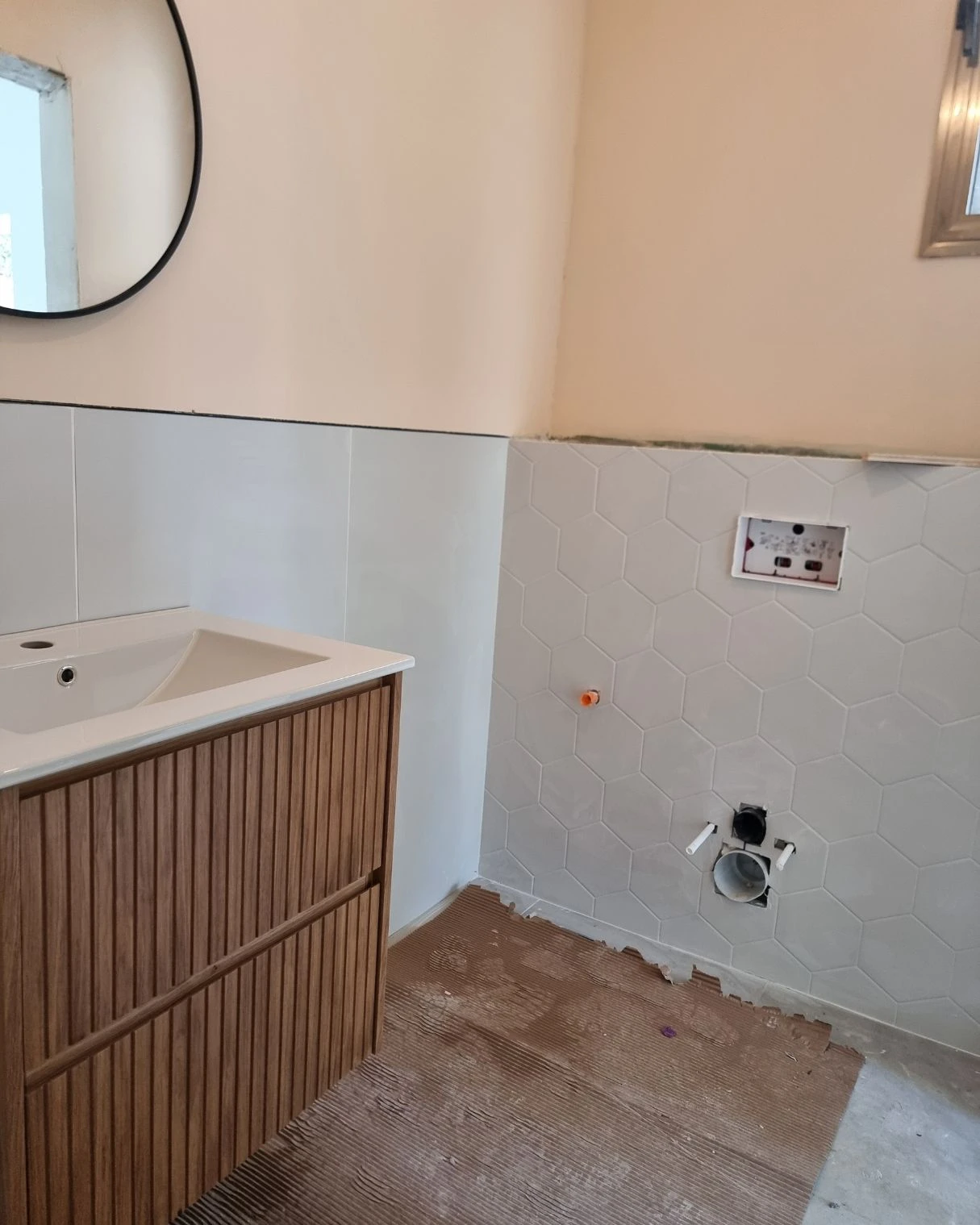 כיור וארון עץ מותקנים בשירותי האורחים לפני גמר הקירות