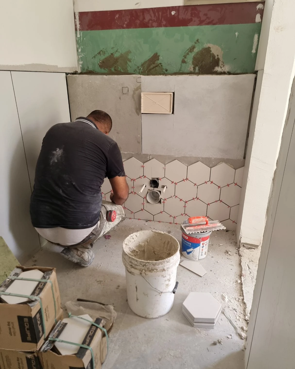 עבודות חיפוי באריחים משושים בחדר שירותים בזמן השיפוץ