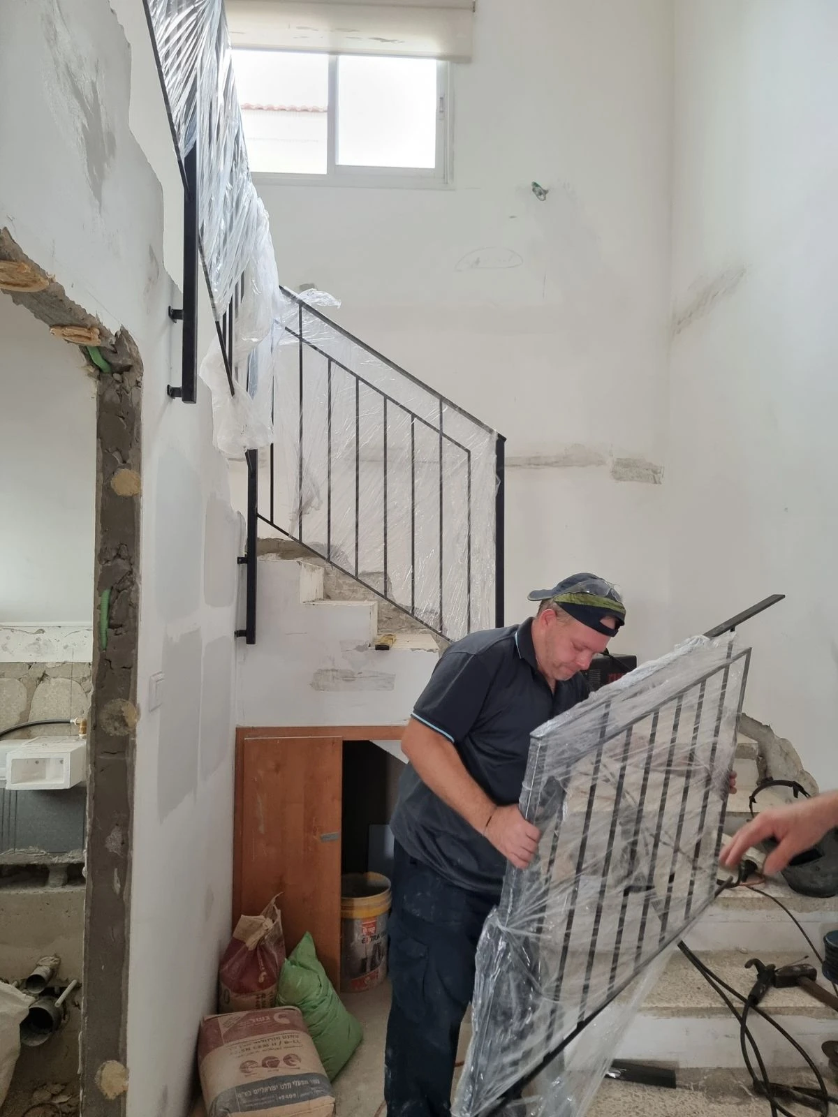 איש מקצוע מתקין מעקה זכוכית עטוף בגרם המדרגות בזמן השיפוץ