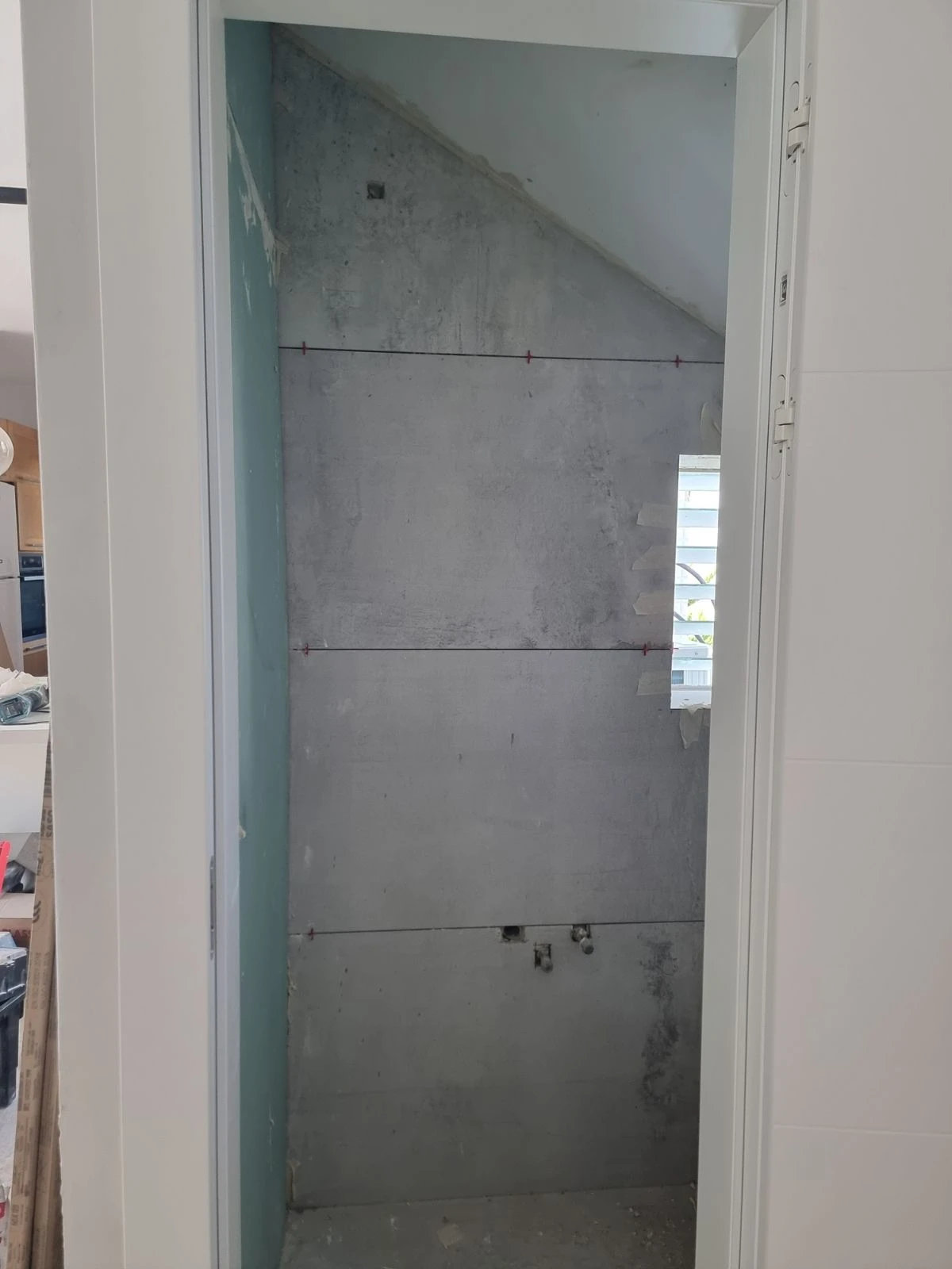 חלל צר עם קיר בטון חשוף וסימוני מדידה לפני חיפוי